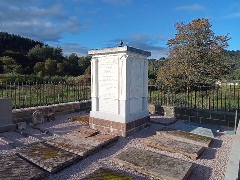 A white monument in a cemetery
      